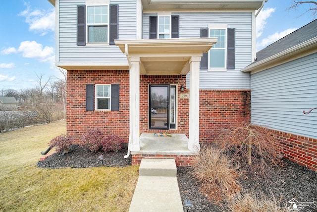 property entrance with a yard and brick siding