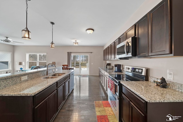 kitchen with a sink, dark brown cabinetry, dark wood-type flooring, appliances with stainless steel finishes, and pendant lighting