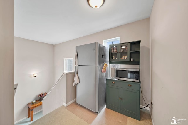 kitchen with green cabinets, glass insert cabinets, baseboards, and stainless steel appliances