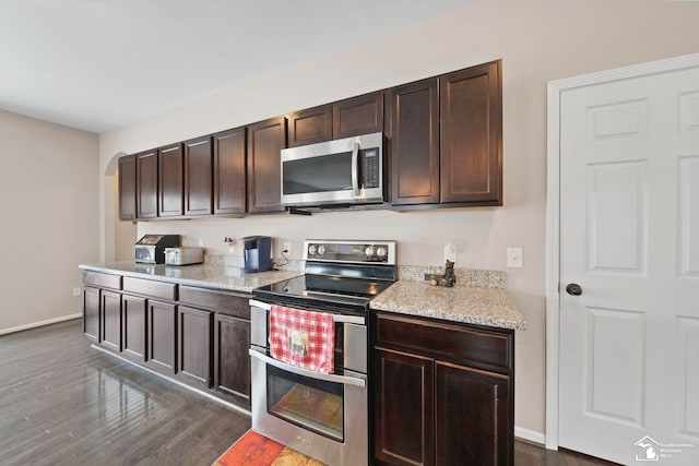 kitchen with dark brown cabinetry, dark wood-style floors, baseboards, and stainless steel appliances