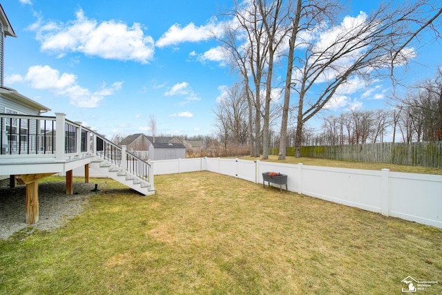 view of yard featuring a deck, stairs, and a fenced backyard