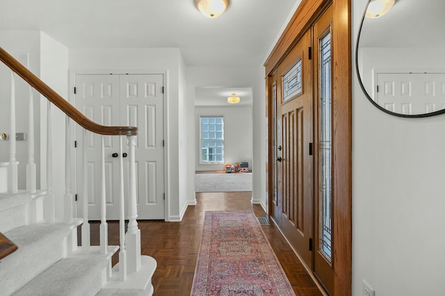 foyer entrance with stairway and baseboards