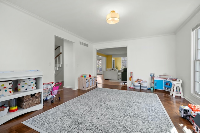 game room with crown molding, a healthy amount of sunlight, visible vents, and baseboards