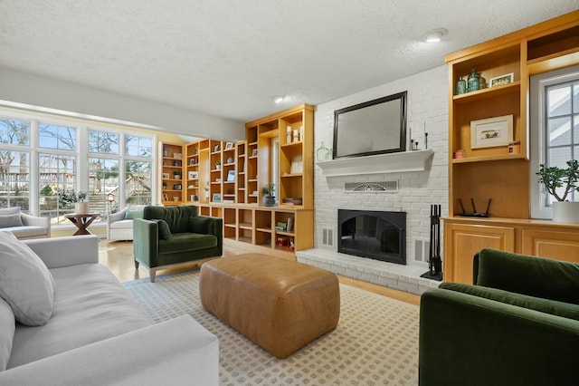 living area with built in features, a healthy amount of sunlight, a brick fireplace, and a textured ceiling