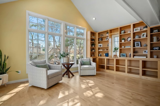 sitting room with visible vents, high vaulted ceiling, baseboards, and wood finished floors