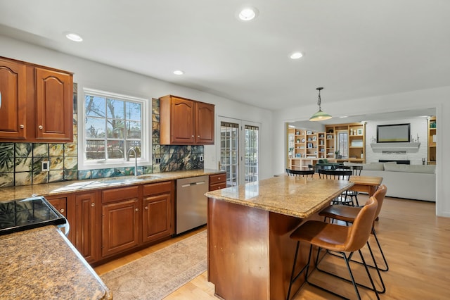 kitchen featuring dishwasher, a kitchen breakfast bar, light wood-style flooring, and a sink