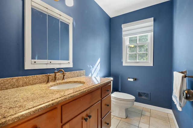 half bathroom featuring tile patterned flooring, toilet, vanity, and baseboards