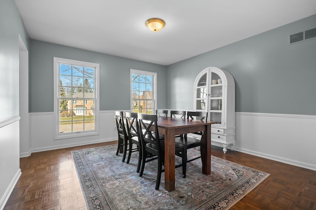 dining area featuring visible vents, baseboards, and wainscoting