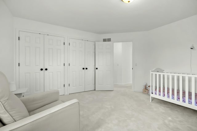 bedroom with carpet, visible vents, and multiple closets