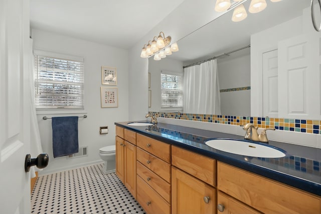 full bath with a sink, decorative backsplash, and toilet