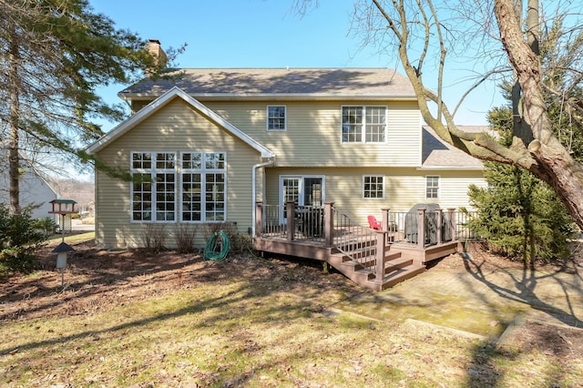 rear view of property with a deck, a yard, and a chimney