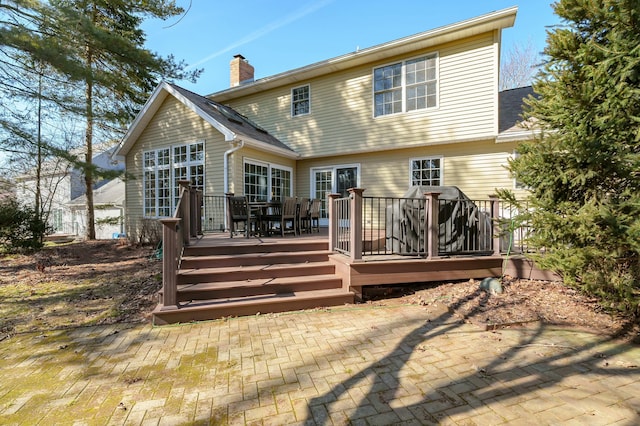 rear view of property featuring a wooden deck and a chimney