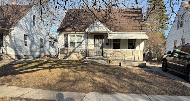 view of front facade featuring a front yard and roof with shingles