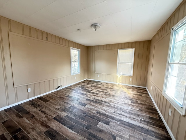 unfurnished room featuring baseboards, plenty of natural light, and wood finished floors