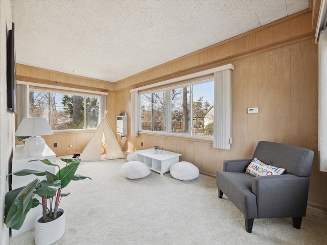 living area with plenty of natural light, wood walls, and carpet floors