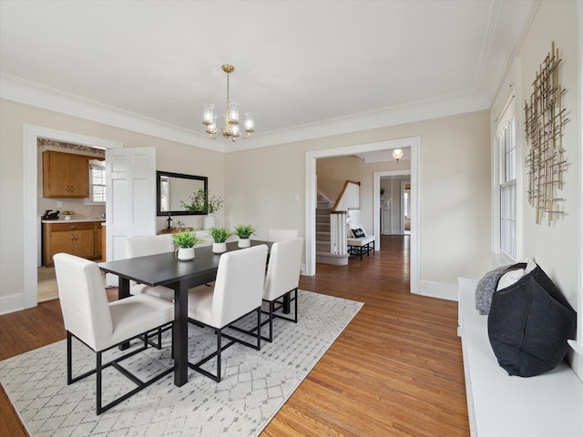 dining space with a notable chandelier, stairway, crown molding, and light wood-type flooring