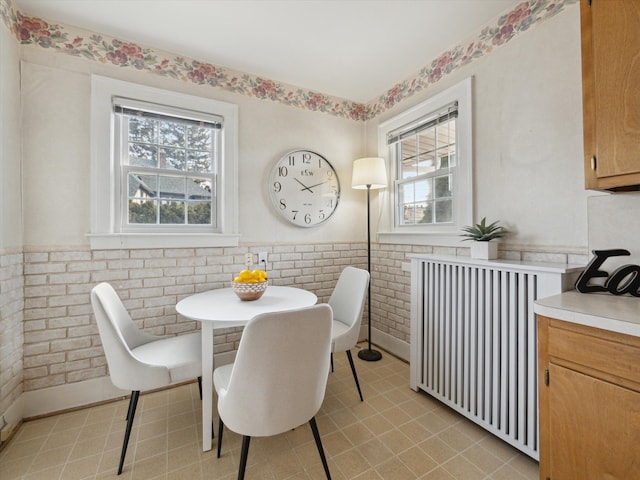 dining area featuring a wainscoted wall, radiator, and light tile patterned flooring