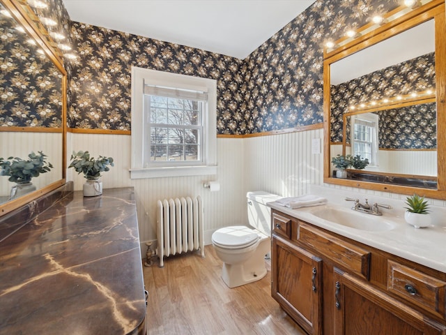 bathroom with wallpapered walls, radiator, and wainscoting