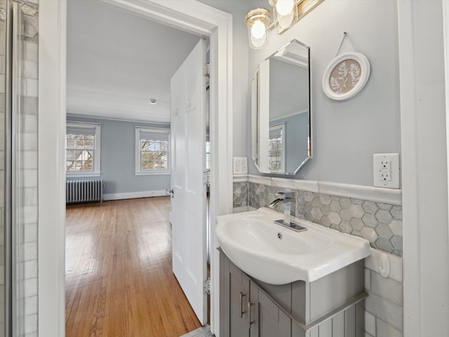 bathroom featuring hardwood / wood-style floors, radiator, tile walls, wainscoting, and vanity