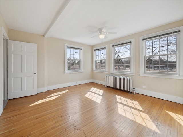 interior space featuring light wood-style flooring, radiator, a ceiling fan, and baseboards