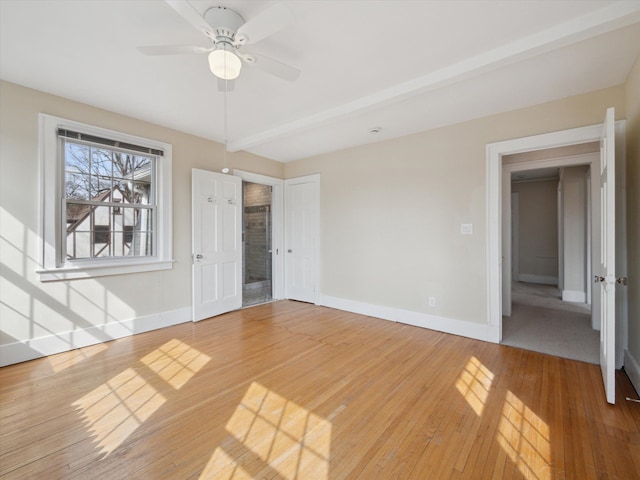 interior space featuring light wood-style flooring, beamed ceiling, baseboards, and ceiling fan