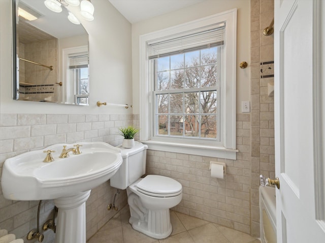 bathroom featuring walk in shower, toilet, wainscoting, tile patterned floors, and tile walls