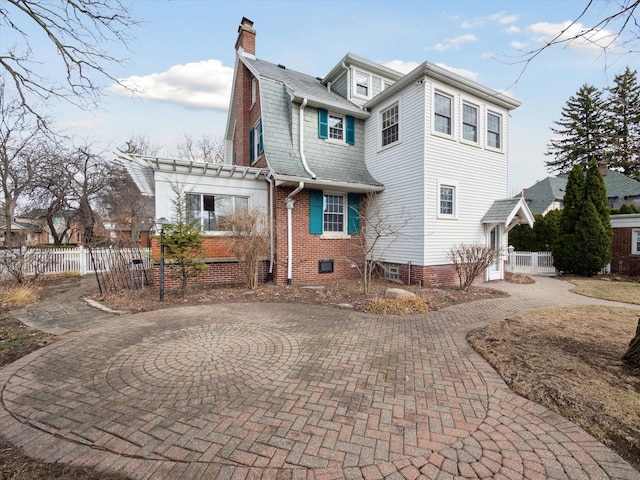 back of property with fence, a gambrel roof, and curved driveway