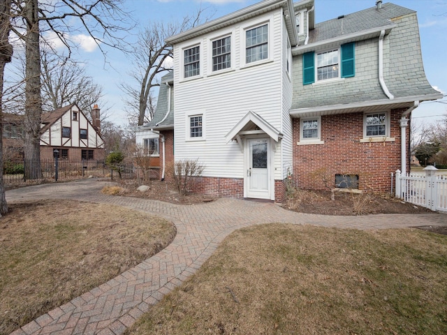 rear view of house featuring a yard, brick siding, and fence