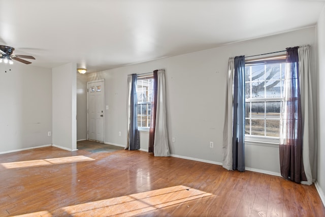 spare room with a ceiling fan, baseboards, and hardwood / wood-style floors