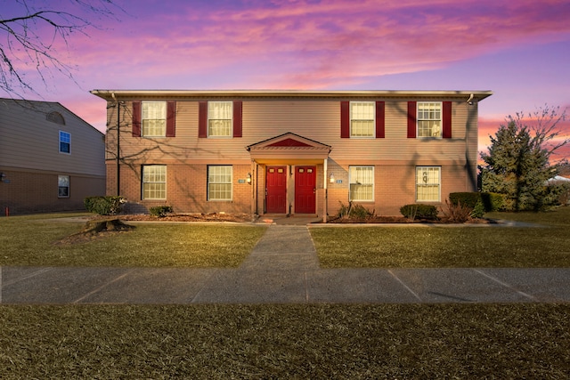 view of front of house with a front yard and brick siding