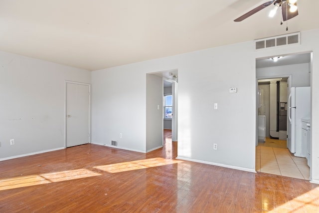 unfurnished bedroom with visible vents, light wood-type flooring, freestanding refrigerator, and baseboards