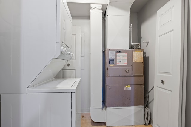 laundry room featuring heating unit, stacked washer and clothes dryer, and laundry area