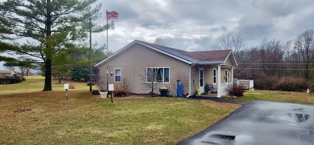 view of side of home with a lawn, covered porch, central AC, and a shingled roof