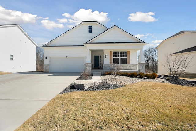 view of front of property with a front lawn, covered porch, a garage, stone siding, and driveway