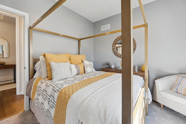 carpeted bedroom featuring visible vents and wood finished floors