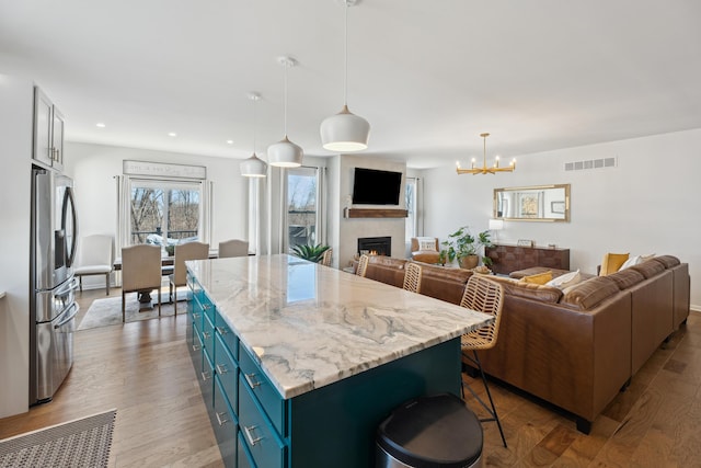 kitchen with blue cabinets, visible vents, stainless steel fridge, and open floor plan