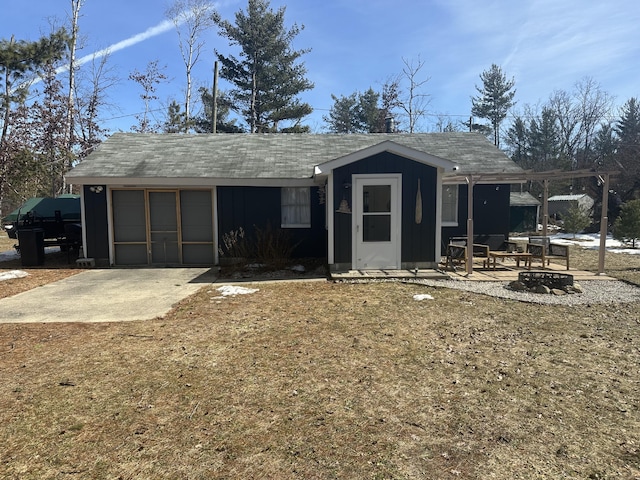 rear view of house featuring a garage, a fire pit, and concrete driveway