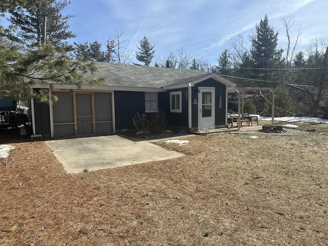 rear view of house featuring an attached garage, driveway, and a shingled roof