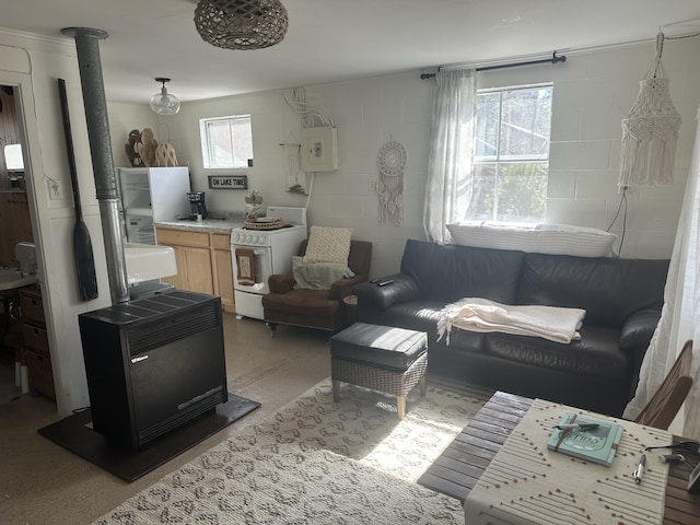 living room featuring a wood stove, concrete block wall, and light speckled floor