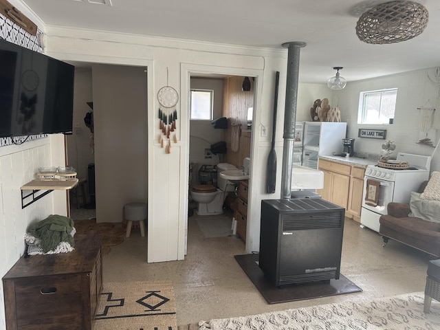 kitchen featuring light brown cabinetry, white gas stove, and a wood stove