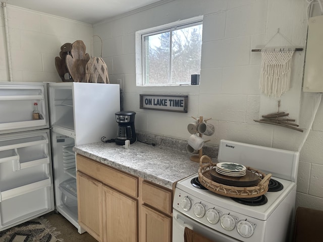 kitchen with white appliances, concrete block wall, and light countertops