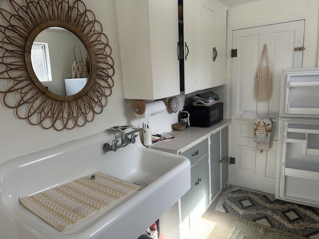 kitchen with white cabinets, light countertops, black microwave, and a sink