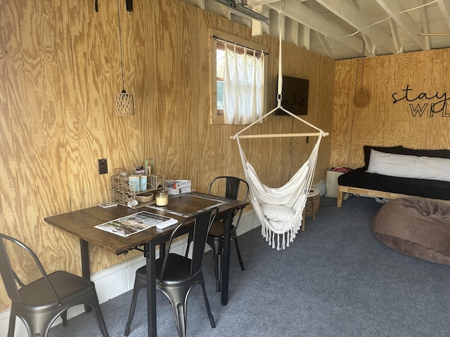 carpeted dining area with wooden walls