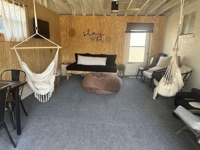 sitting room with wooden walls, concrete block wall, and carpet