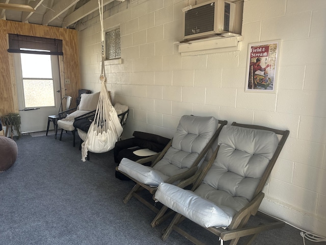 living area with carpet floors and concrete block wall