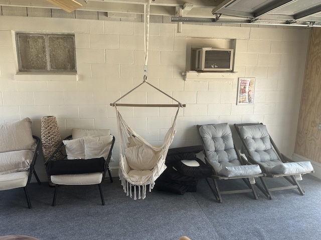 living area with concrete block wall, carpet flooring, and a wall unit AC