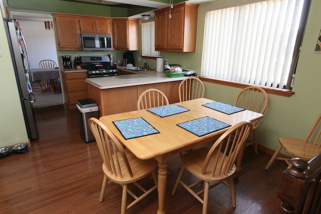 kitchen featuring dark wood-type flooring, light countertops, a peninsula, stainless steel appliances, and a sink