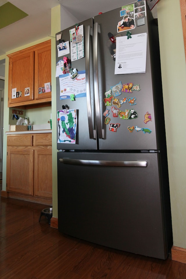 kitchen featuring brown cabinetry, dark wood-style floors, light countertops, and freestanding refrigerator