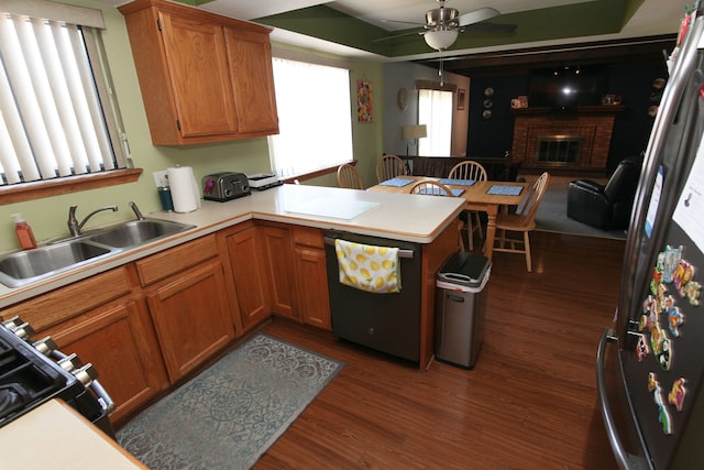 kitchen featuring ceiling fan, dark wood finished floors, light countertops, a peninsula, and a sink