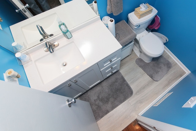 bathroom with toilet, vanity, and wood finished floors